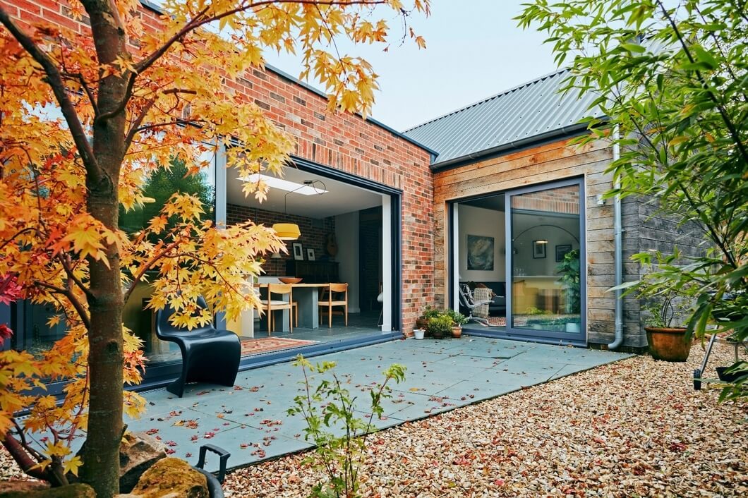 Side perspective of self-build home showcasing Slate Blue Cladco steel roofing and red brickwork