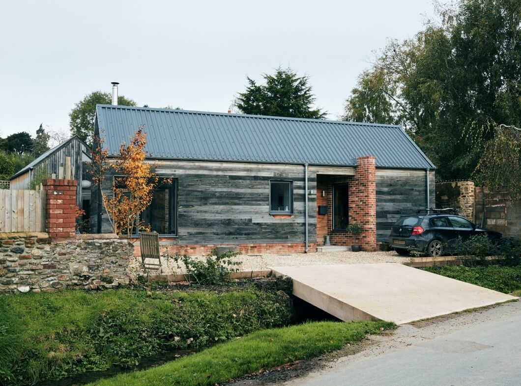 Front view of modern rural self-build home with Slate Blue Cladco Box Profile steel roofing and timber cladding