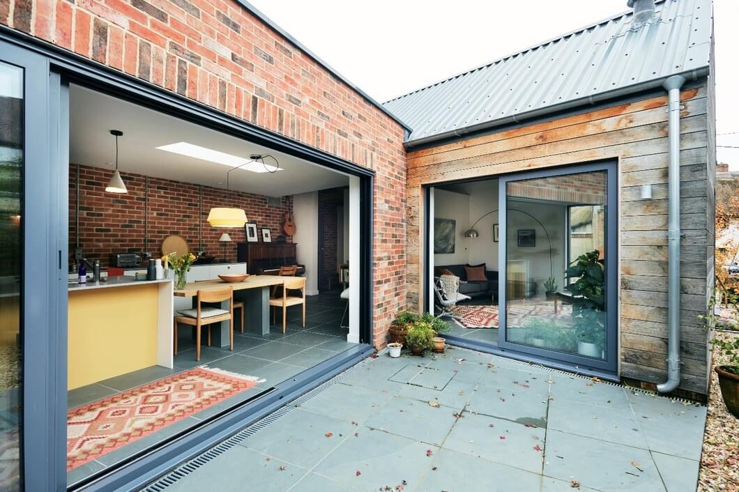 Rear view of self-build home featuring large glass windows and Slate Blue Cladco steel roofing