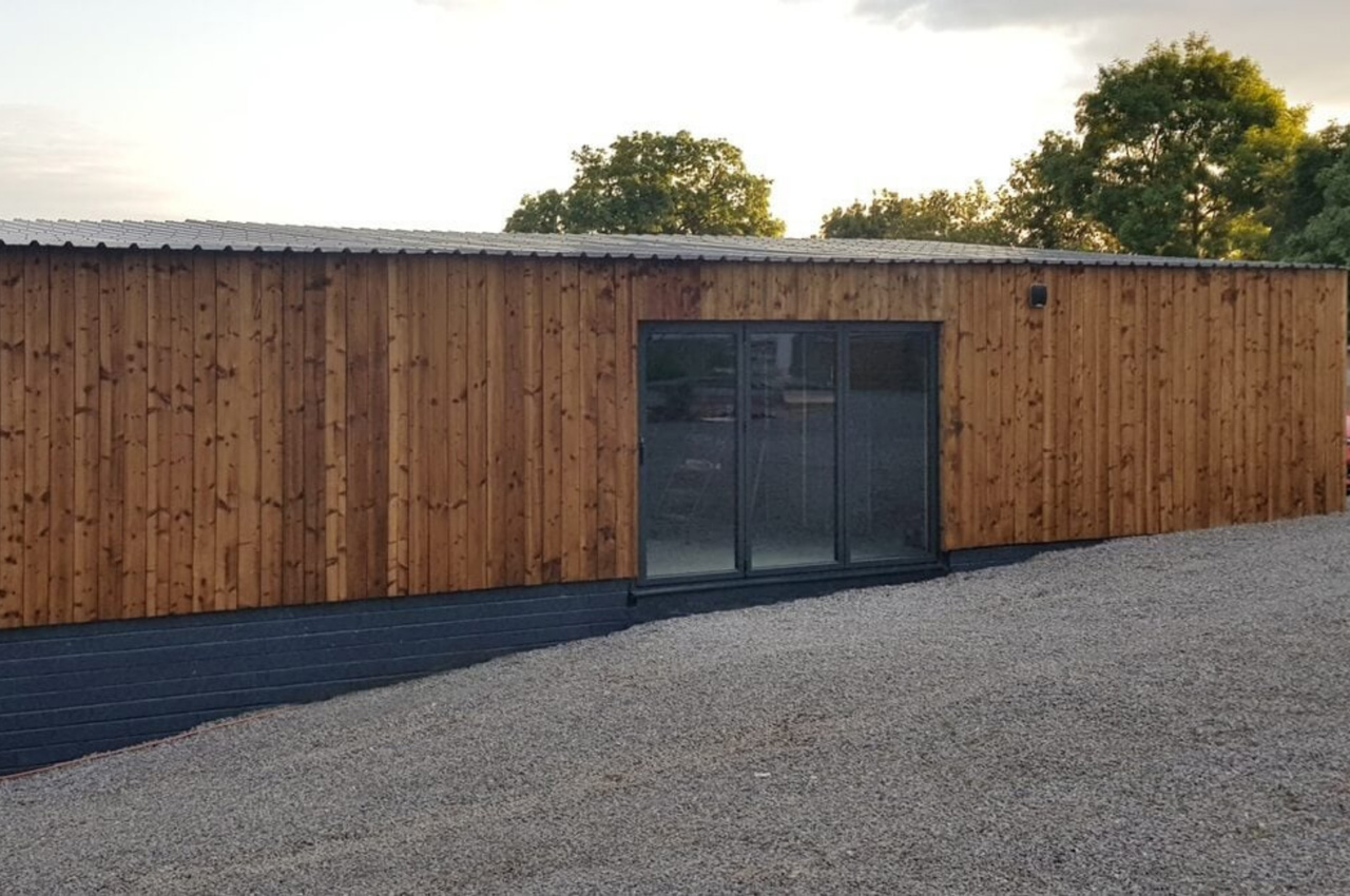 32/1000 Box Profile Roofing Sheets in Black contrast this timber-clad building