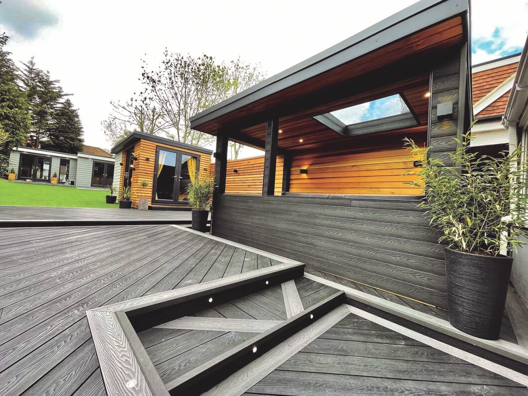 Multi-level garden featuring Cladco Charcoal and Stone Grey Composite Woodgrain Decking Boards with picture frame edging and arrow-shaped steps, installed by Logan Carpentry