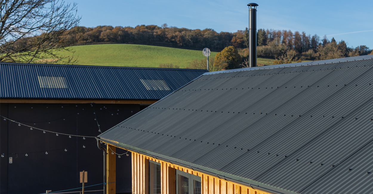 Close-up view of Cladco 13/3 corrugated steel roofing sheets with black PVC Plastisol finish on The Dartmoor Shepherd's farm buildings
