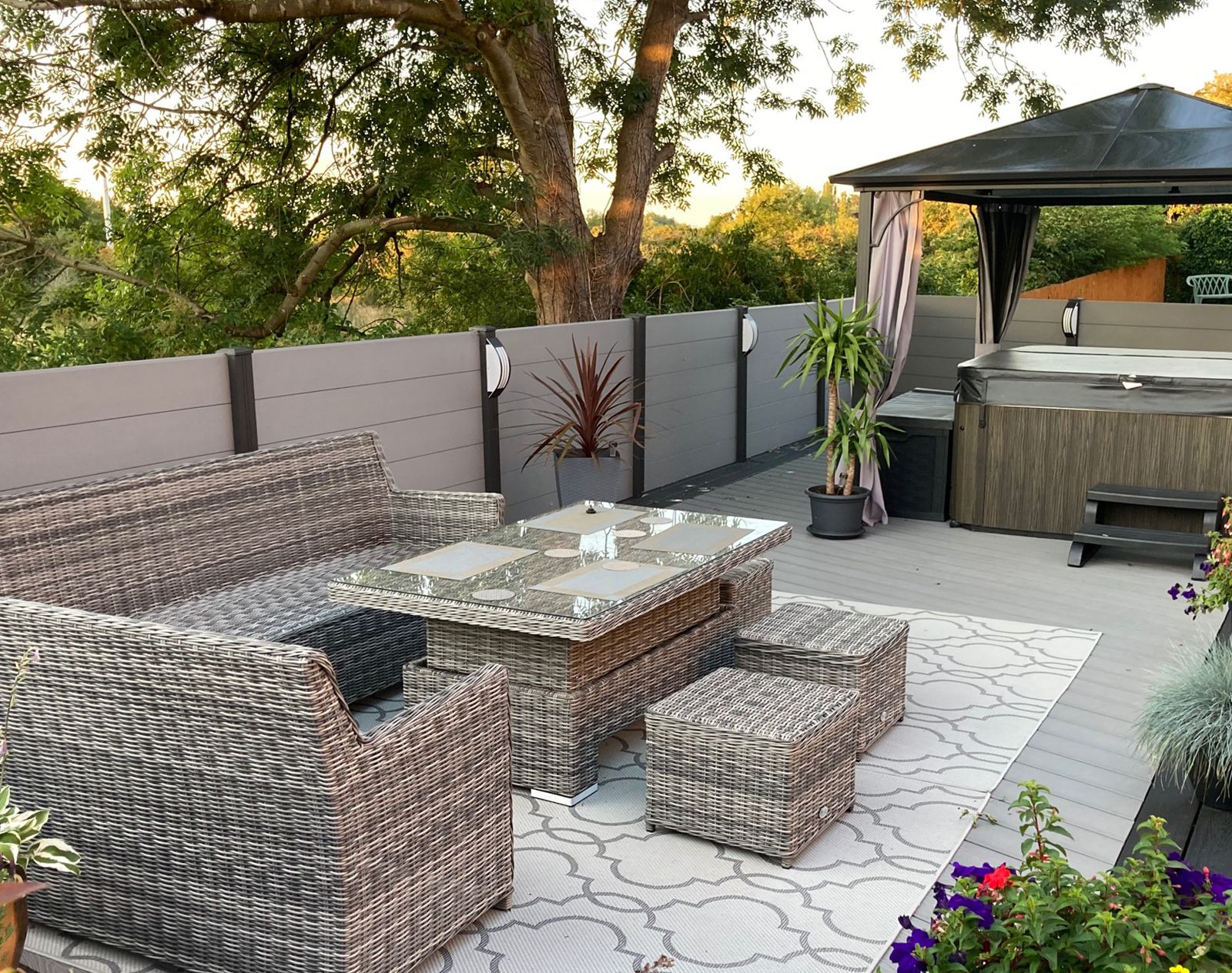 Light grey composite fencing surrounding a garden seating area with rattan furniture, outdoor rug, hot tub, and pergola, creating a stylish and private relaxation space.
