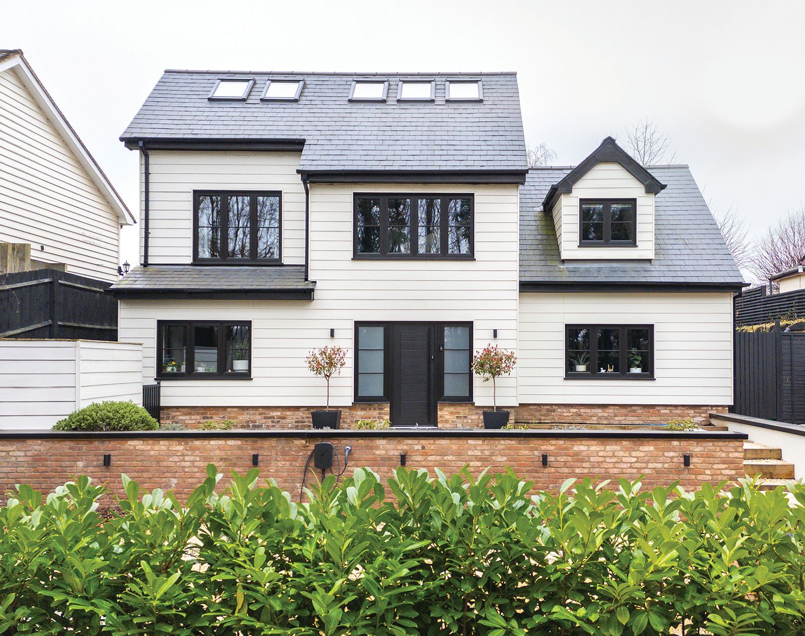 Modern detached home finished with white horizontal fibre cement cladding, black window frames, and a brick ground floor facade for a clean, contemporary look.