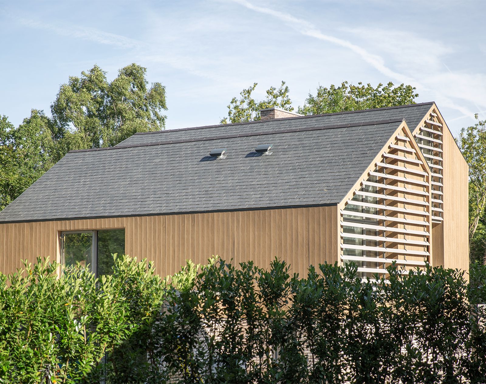 Modern home clad in vertical Millboard cladding with louvred gable feature, highlighting low-maintenance wood-effect composite panels.