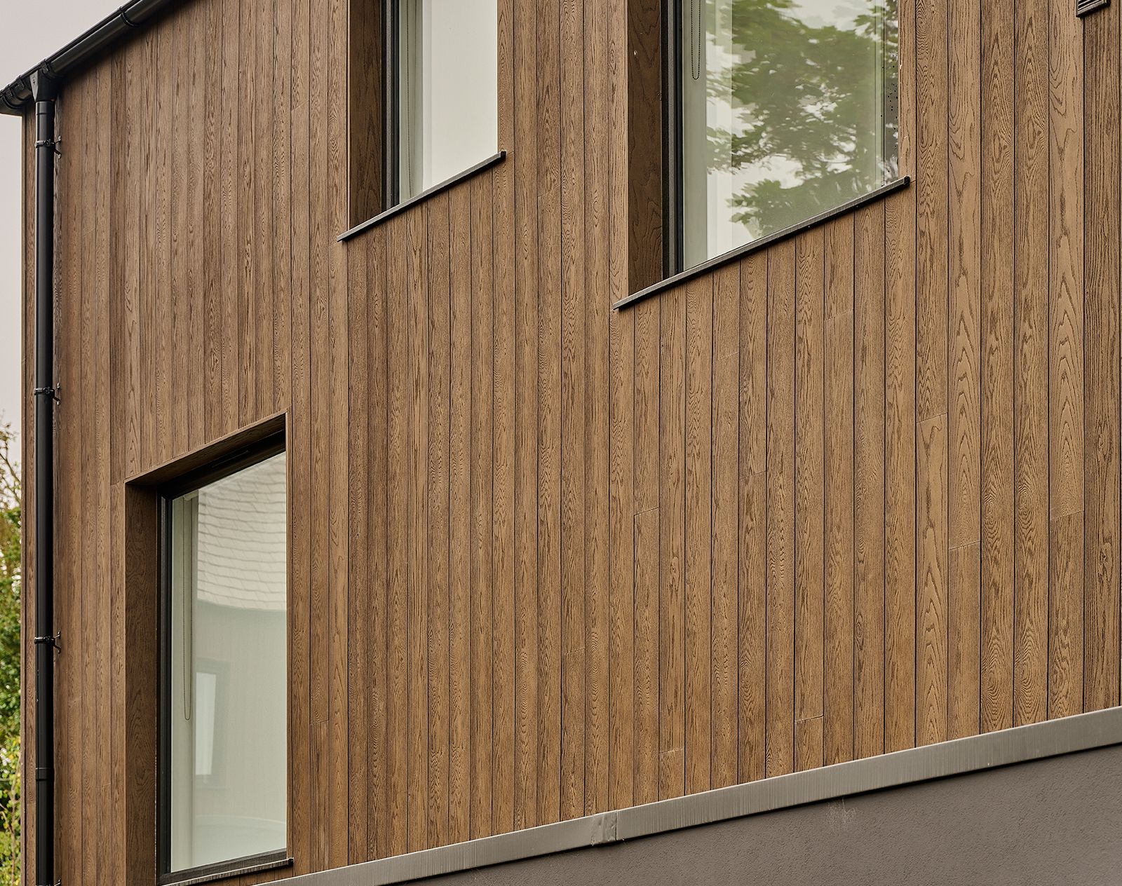 Contemporary house exterior clad in vertical Millboard cladding with natural wood grain finish, highlighting modern design and low-maintenance durability.