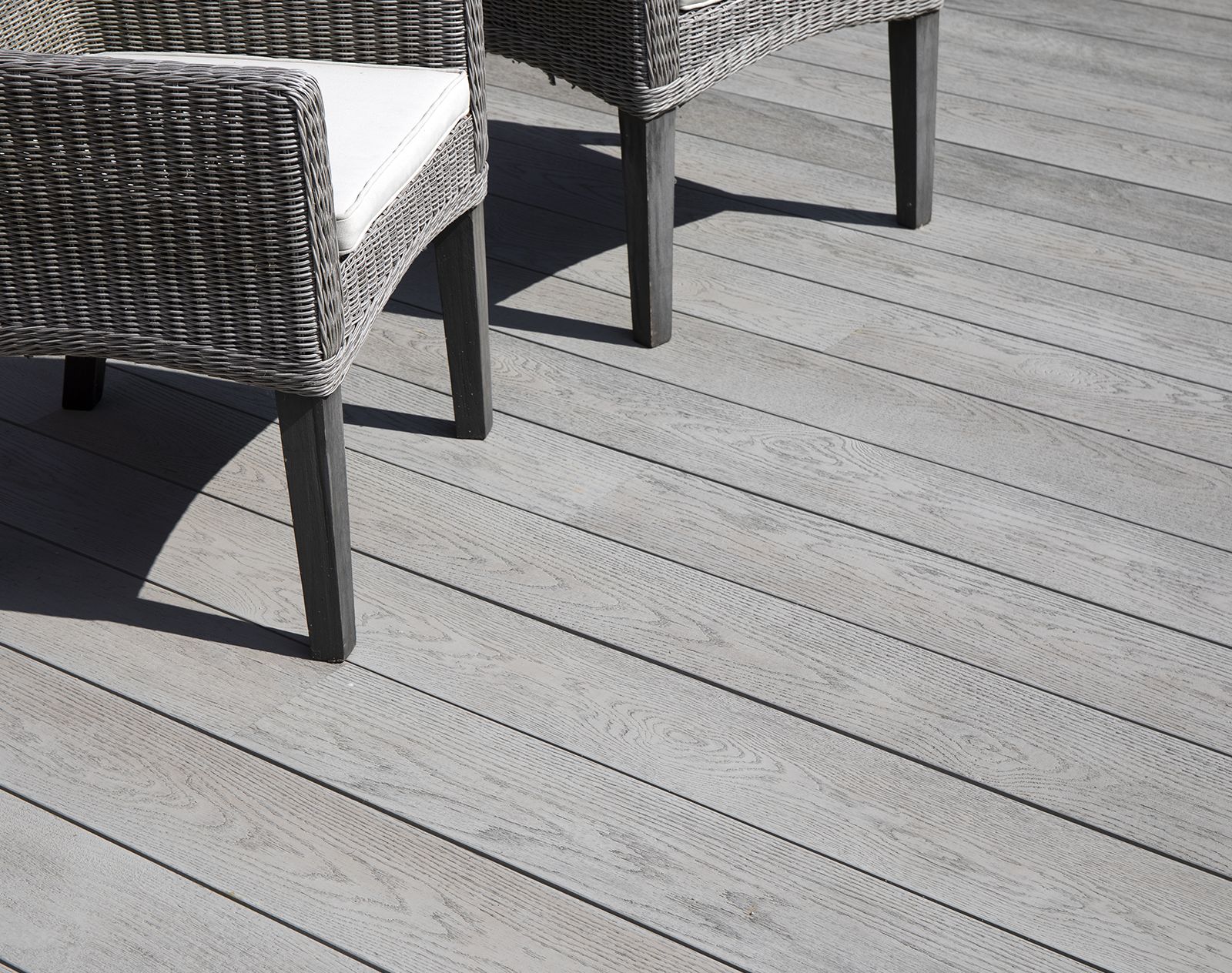 Light grey Millboard decking with wicker outdoor chairs, showcasing a clean and contemporary garden seating area.