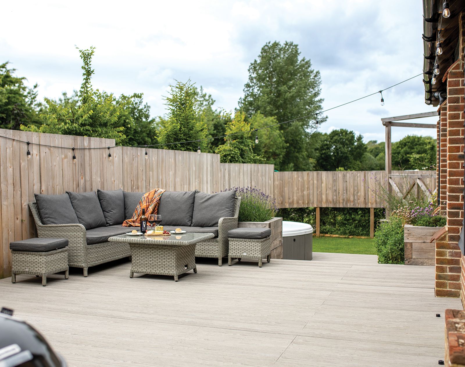 Spacious garden patio with rattan furniture, hot tub, and pale grey Nordeck PVC decking, offering a durable and modern outdoor living space.