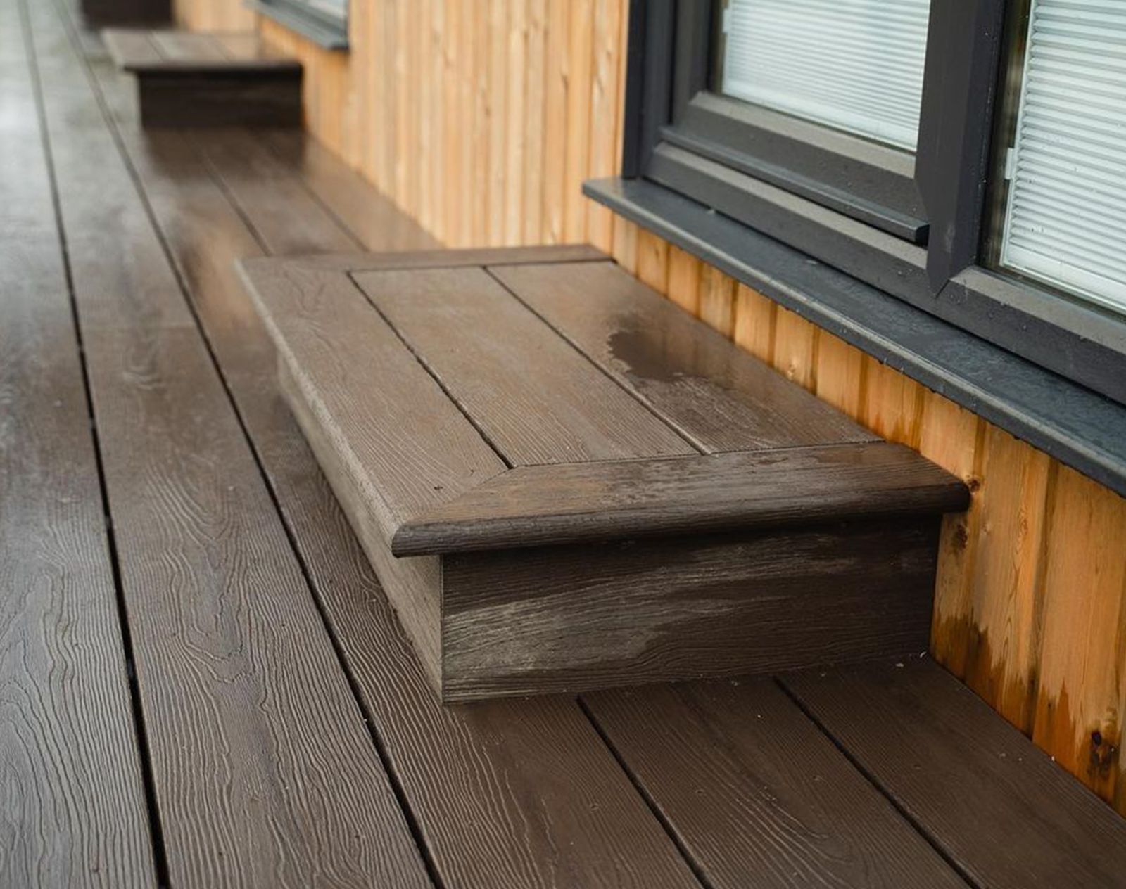 Dark brown Nordeck PVC decking with matching step detail, installed beside modern timber cladding and black-framed windows.