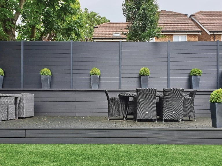 Grey composite fencing in modern garden with decking