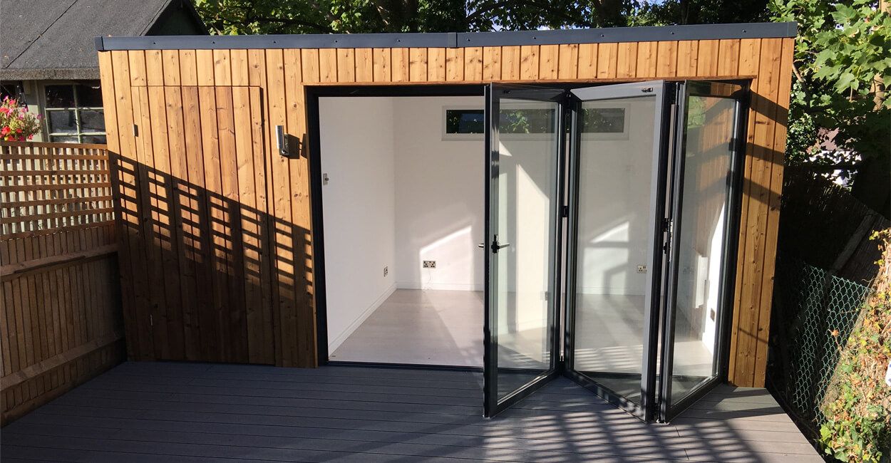 Modern garden room featuring Cladco Stone Grey composite decking and timber cladding by Ark Design Build.