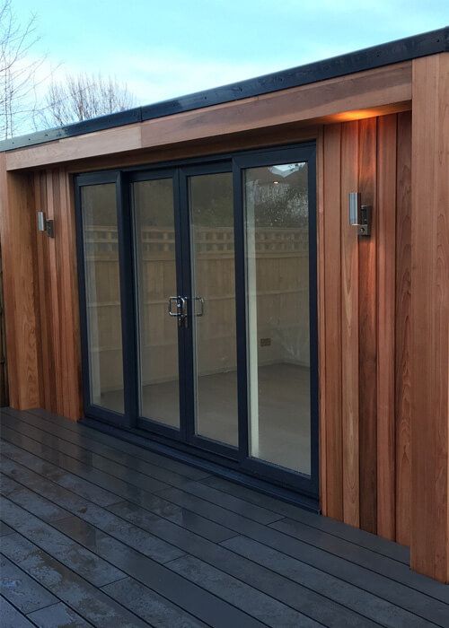 Side perspective highlighting the integration of Cladco composite decking with vertical timber cladding on the garden room.