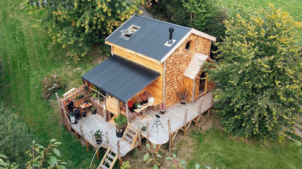 Ursa Bear Cabin nestled in Devon woodland, featuring Cladco Black PVC Plastisol corrugated steel roofing and handcrafted timber shingles