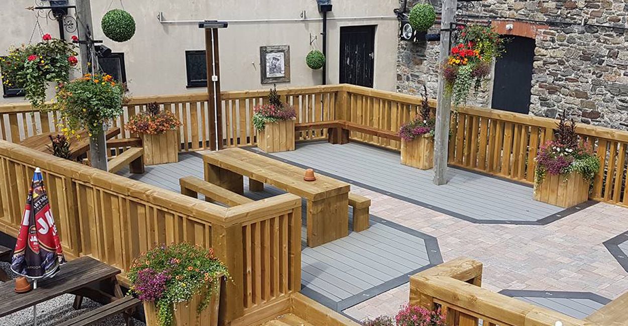 Elevated garden area at Fountain Inn, Okehampton, featuring Cladco composite decking with integrated timber seating and planters.