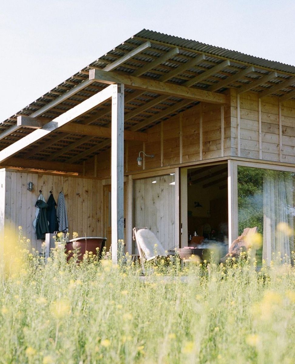 Holly Water Cabin illuminated at dusk, highlighting Cladco corrugated steel roofing and sustainable design elements