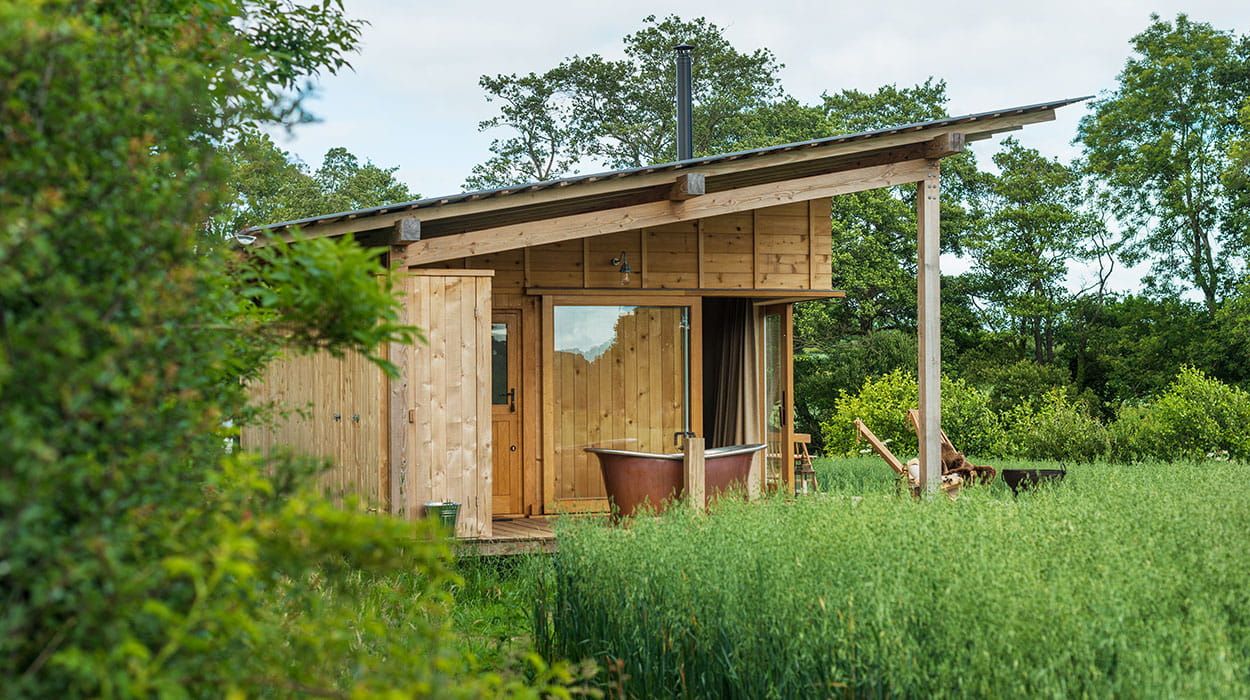 Eco-conscious Holly Water Cabin in Devon with Cladco corrugated steel roofing, timber cladding, and outdoor copper bathtub, designed by Out of the Valley