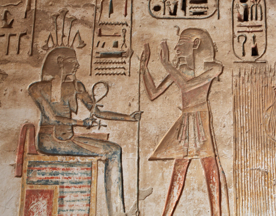 Hieroglyphics of two figures talking to each other, one sat and one stood.