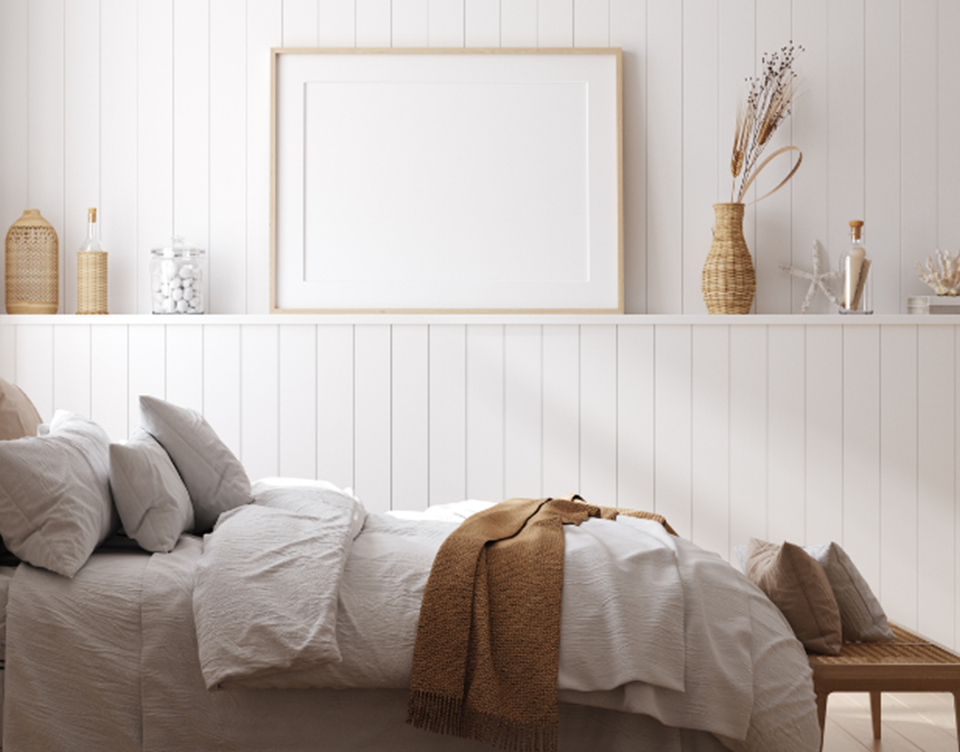 Side view of a bed with white wood wall panelling