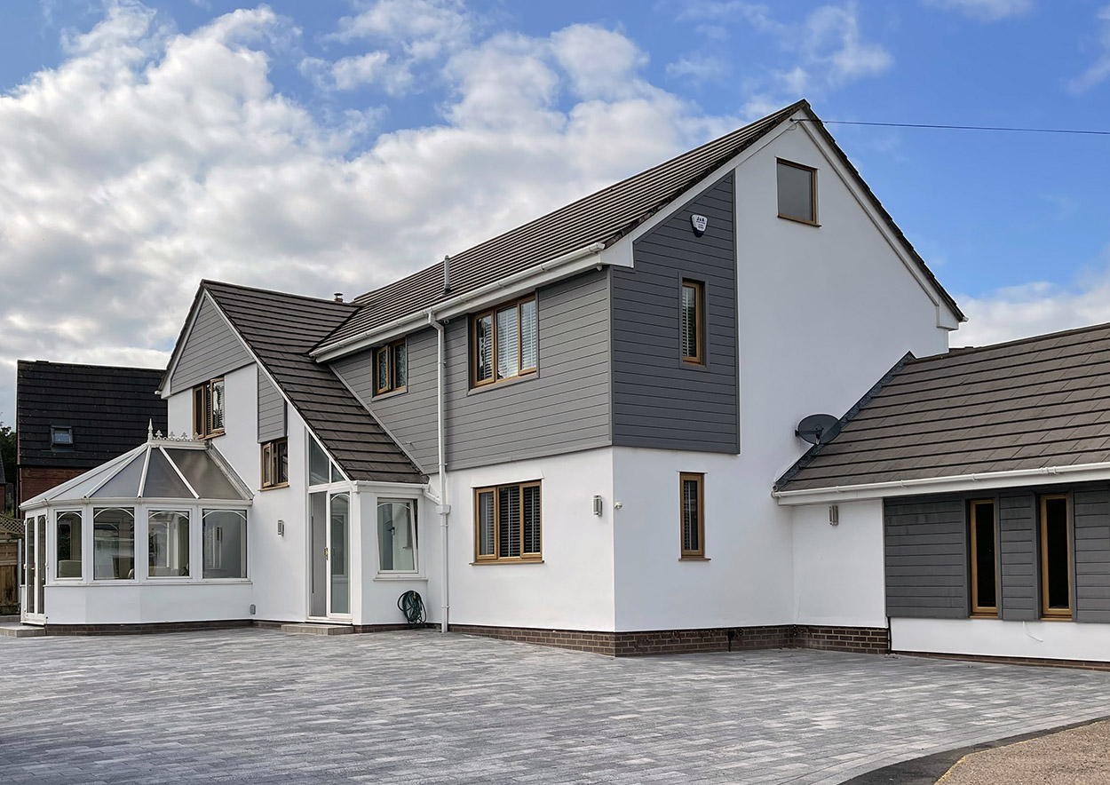A large family home clad with Stone Grey Composite Cladding across segments of the fascia, sides and garage for a modern aesthetic.