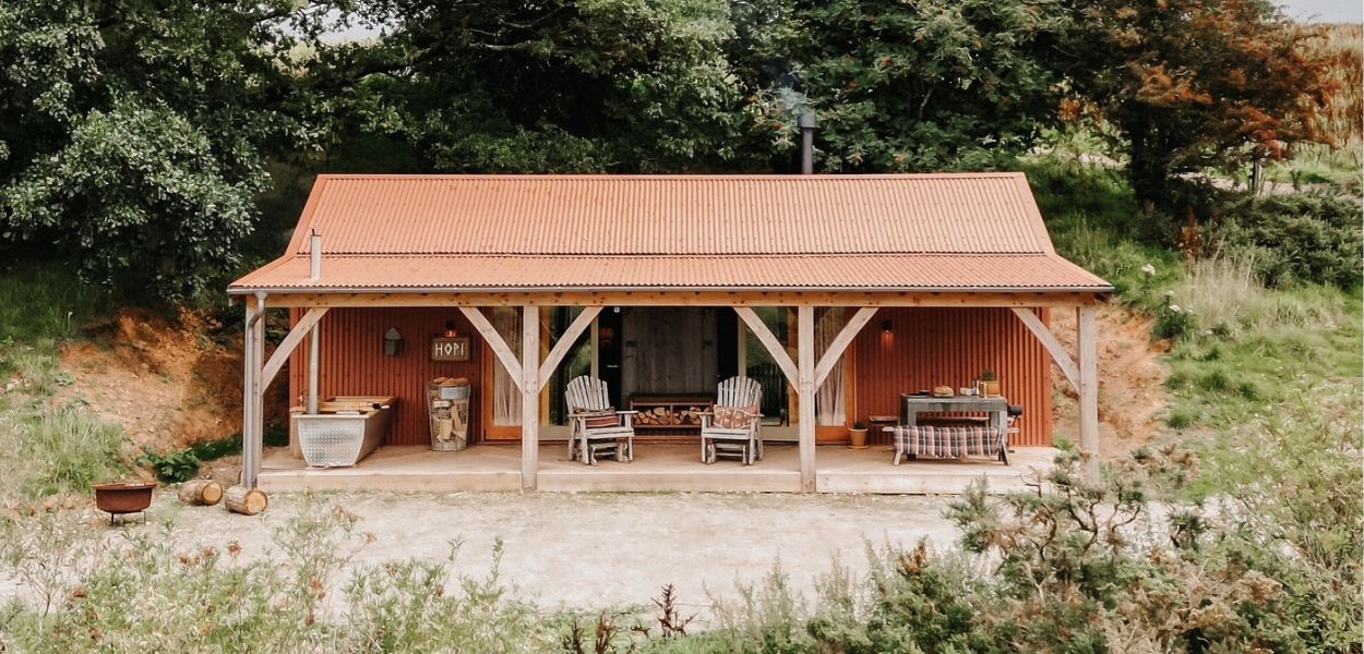 Hopi cabin at Cove Valley utilizing Chestnut PVC Plastisol coated Cladco corrugated steel sheets, harmonizing with the natural surroundings