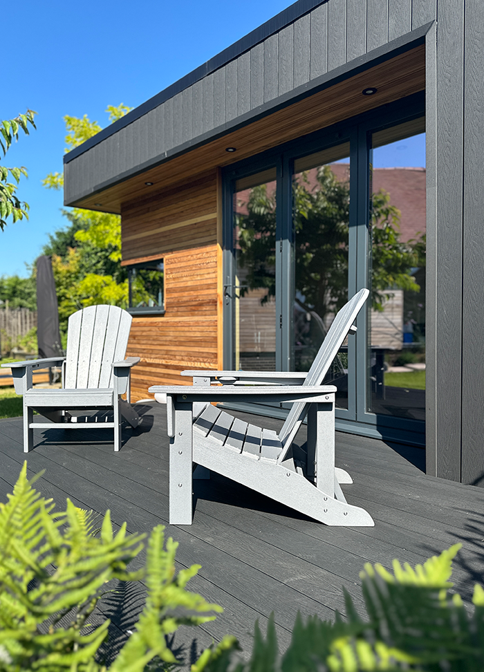 Garden room with a Composite Deck in Charcoal with wooden chairs.