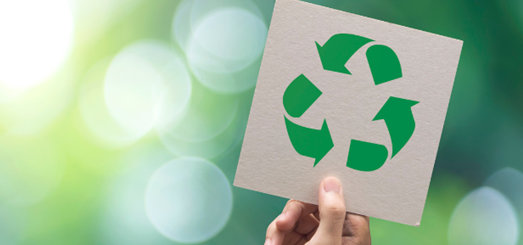 Hand holding up a sign with the recycling symbol on it.