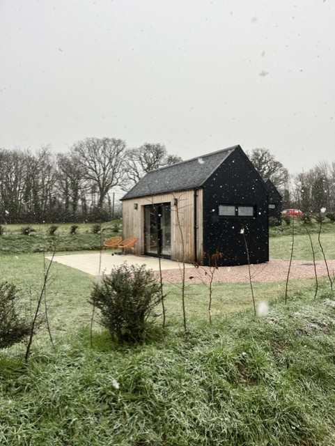 Black Corrugated Cladding lodge with snow falling around.